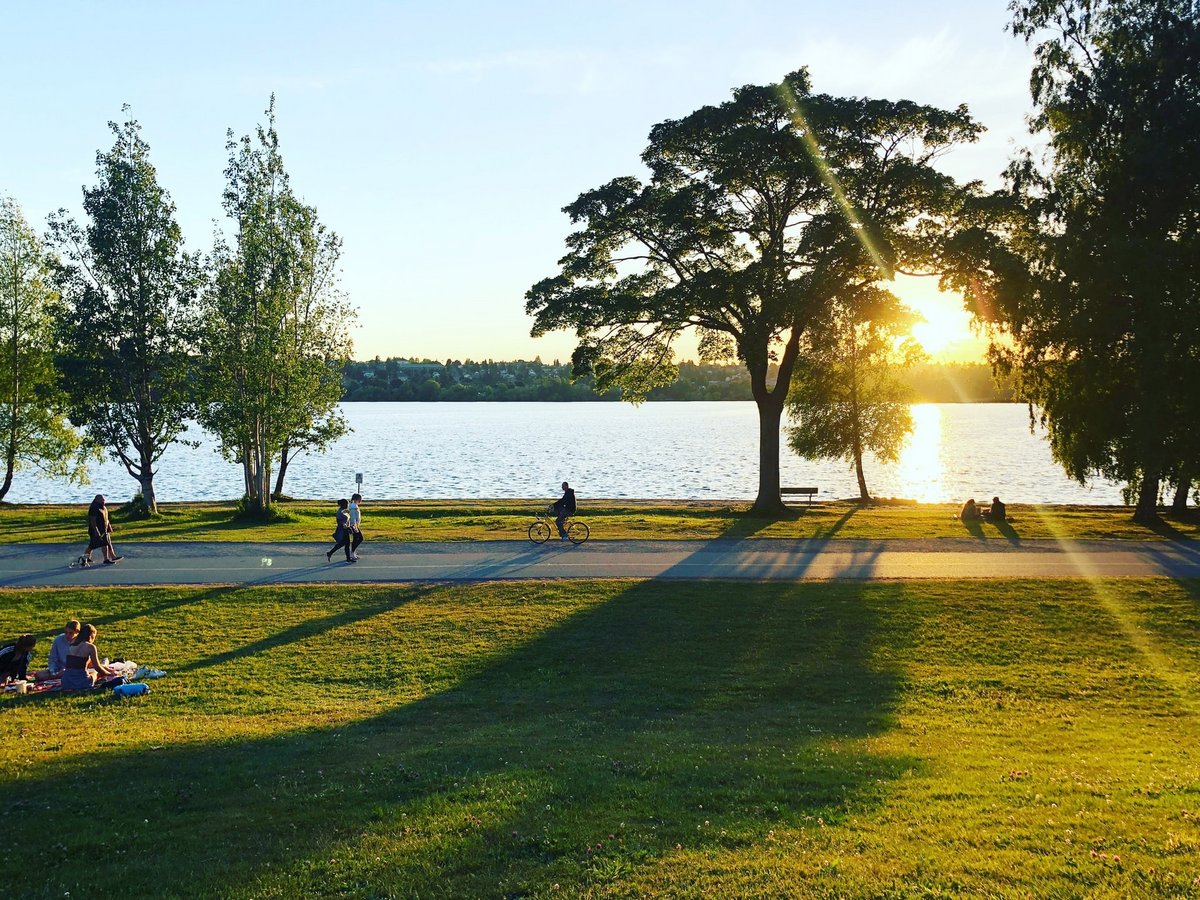 Sonnenuntergang am See, Personen sitzen am Ufer oder joggen den Weg entlang